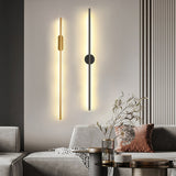 Modern wall sconce in a living room setting with a gray sofa and decorative elements.