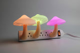 Colorful mushroom-shaped night lights with a power outlet base on a dark background.