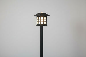 Garden lamp post with a wooden fence and blurred background