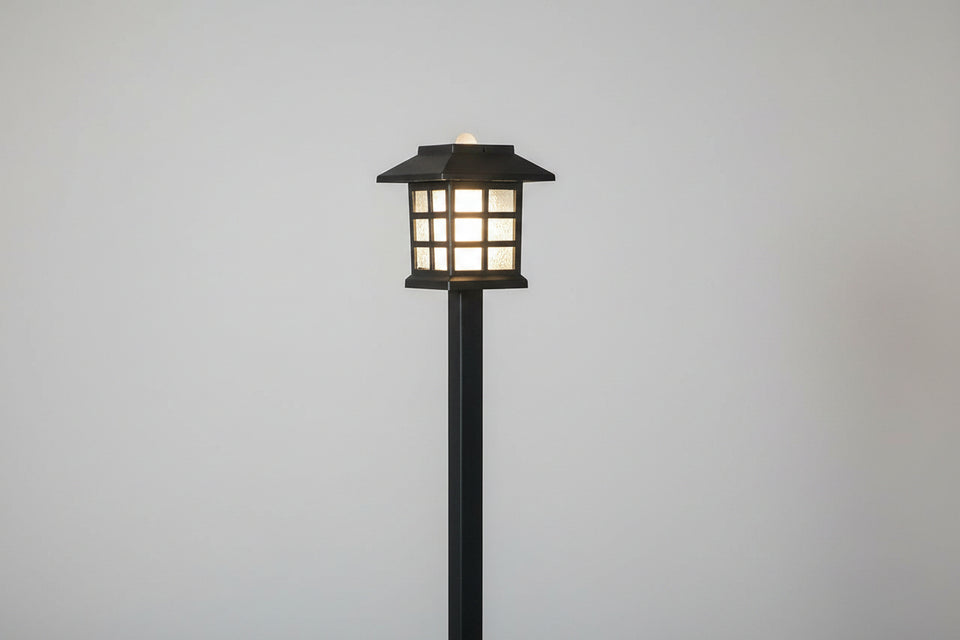Garden lamp post with a wooden fence and blurred background